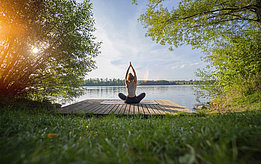 A woman is doing yoga at a lake